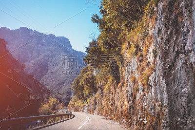 在一个阳光明媚的日子里，透过挡风玻璃可以看到美丽的山景。在欧罗巴国家公园蜿蜒的山路上开车。坎塔布里亚