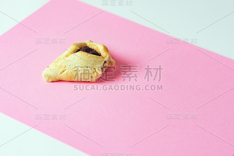 一个Hamentashen, Ozen Haman，犹太节日普林节的粉色背景上的普林节饼干