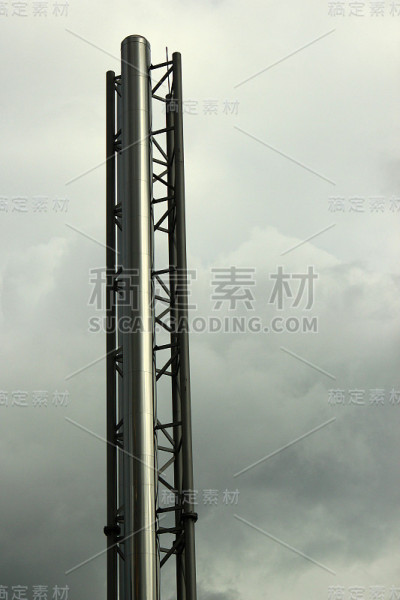 在阴天的背景下，支撑架上有闪亮的金属烟囱管