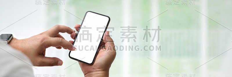 近距离观察商人使用空白屏幕智能手机在玻璃墙办公室的房间