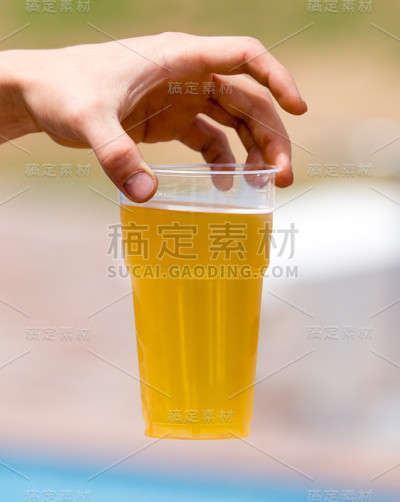 手里拿着塑料杯的新鲜啤酒