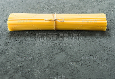 生意大利面意大利面与一根绳子绑在黑色纹理的背景。