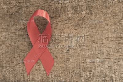 艾滋病红丝带。孤立的木制背景与空白的文字。