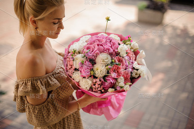 手捧一束白色和粉红色的花的女人