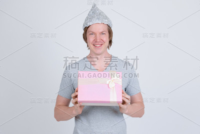 快乐的年轻人用锡纸帽拿着礼盒