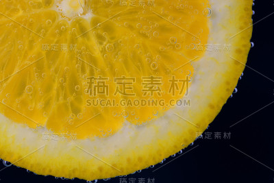 一个新鲜的橙子片在水下漂浮着气泡，产生新鲜的柠檬水。