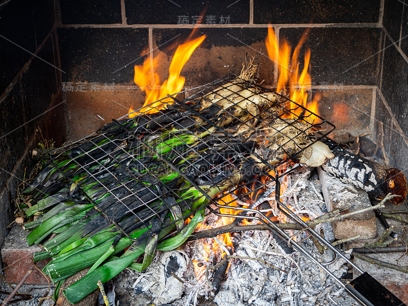 一串calçots(典型的加泰罗尼亚冬葱或大葱)在烧烤时被烤熟