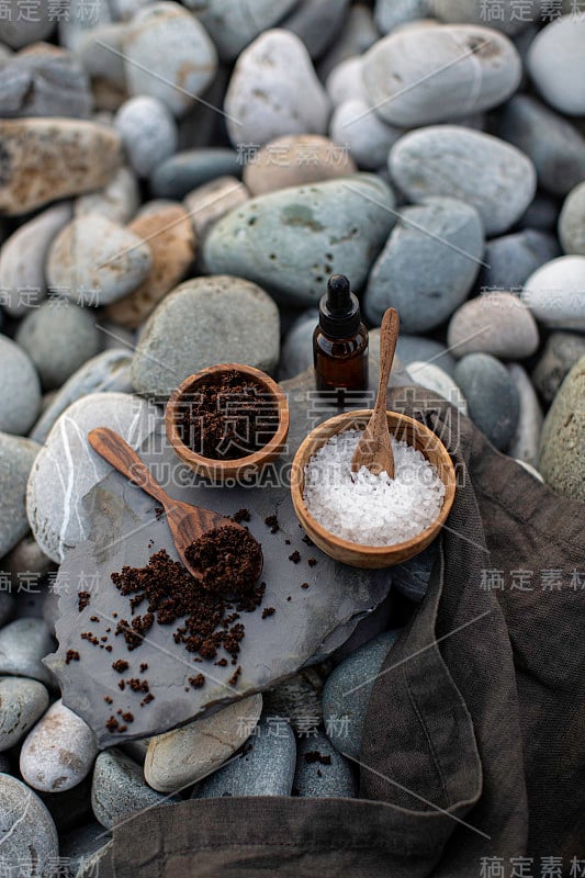 准备自制的咖啡磨砂，用喜马拉雅盐和CBD油在海卵石的背景-库存照片