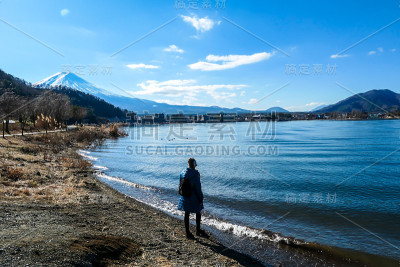 日本——一名女子站在川口町湖边，眺望富士山