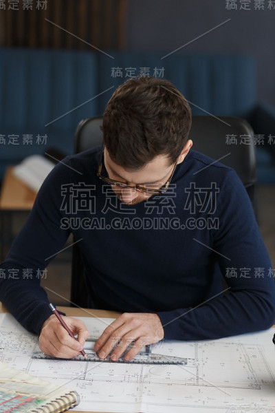 建筑师在办公室里设计蓝图。工程师检查建筑平面图，为建筑工程画草图。长着胡须的英俊男子坐在工作场所的肖