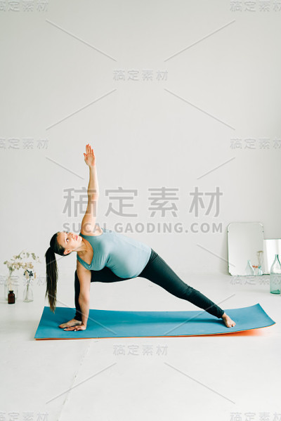年轻孕妇穿着运动服在瑜伽室做体式