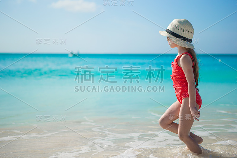 可爱的小女孩在异国海滩的浅水里玩耍