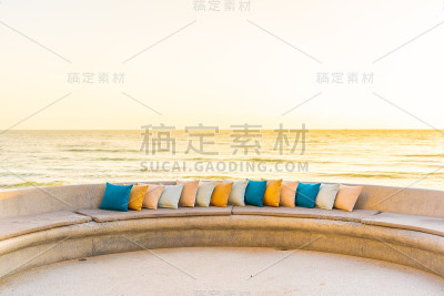 舒适的枕头在沙发椅周围的户外露台与海洋海滩的看法