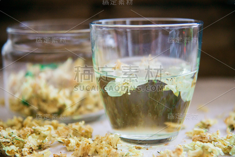 绿色背景木桌上的茉莉花绿茶杯和茶壶