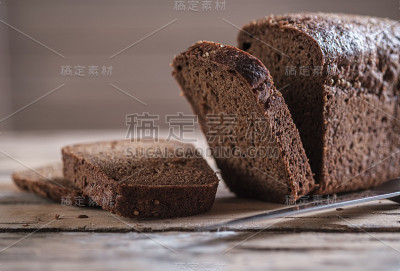 长方形黑麦面包和香菜放在木桌上。切片面包