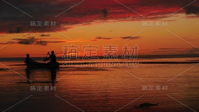 宽镜头与剪影的两个船夫在海上与戏剧性的日落背景