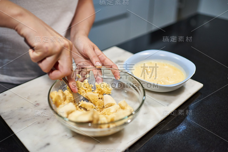 一个女人的手压碎香蕉做香蕉煎饼的特写