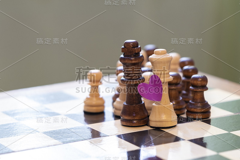 棋盘上的棋子白色的皇后和黑色的国王有一个心形的象征。异族间的爱情、婚姻和家庭的概念