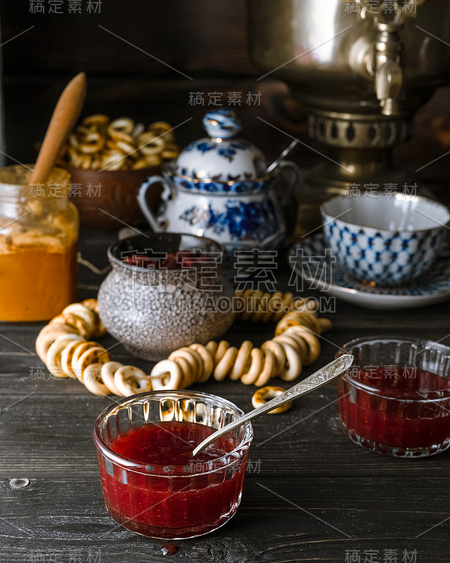 传统的俄罗斯茶几设置与果酱，蜂蜜，百吉饼在黑暗的乡村背景