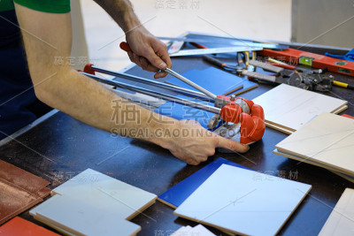 男性用手在桌子上用手切瓦片切割建筑材料