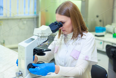 在科学实验室使用显微镜工作的实验室助理。新型冠状病毒肺炎COVID冠状病毒