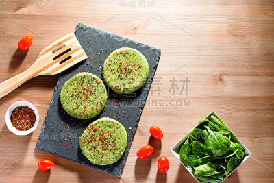 在强光下，石盘上放着生的绿色鸡肉和香料菠菜汉堡，俯视图。饮食健康理念，晚餐节食理念，减肥友好食品，乡
