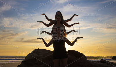 四个美丽的女人在日落或日出时在海滩上的岩石上创造印度教女神的轮廓。