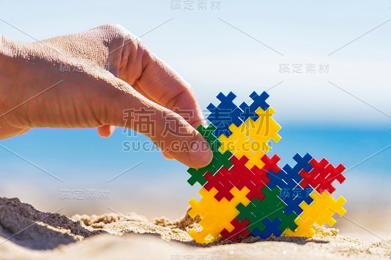 自闭症友好的假期。女性手与彩色自闭症意识心与阳光海滩海洋背景