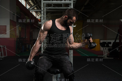 用哑铃锻炼二头肌的年轻人