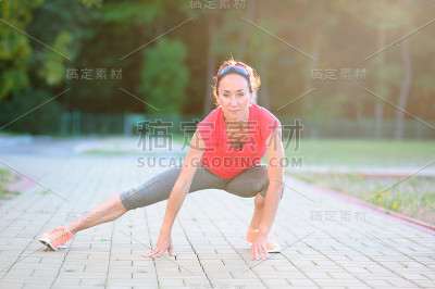 健身女孩跑步前伸展双腿