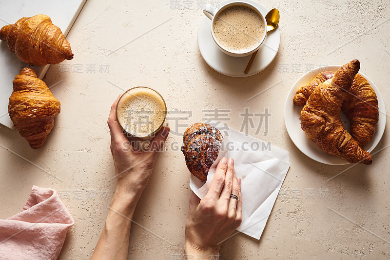 咖啡和羊角面包。早餐饮料与糕点。女士手里拿着一杯拿铁。早上集合