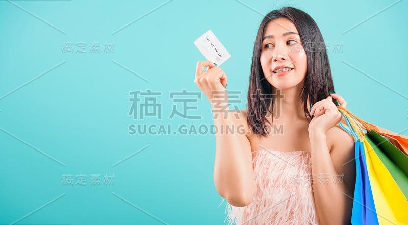 肖像亚洲美丽的女人微笑着拿着购物袋和信用卡和她看信用卡