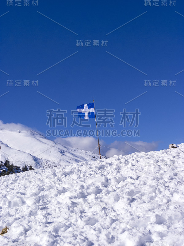 希腊国旗在齐里亚山覆盖着积雪的一个冬日，南伯罗奔尼撒，希腊