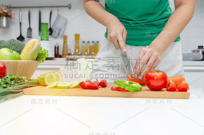 饮食。年轻漂亮的女人在绿色衬衫切割烹饪和刀准备新鲜蔬菜沙拉在厨房在家里，健康的生活方式，烹饪，健康的
