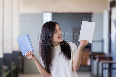 亚洲妇女拿着书在学校走廊里与模糊的背景