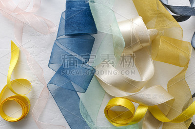 蓝色，黄色，米黄色，粉色，绿色缎带在明亮的表面的特写