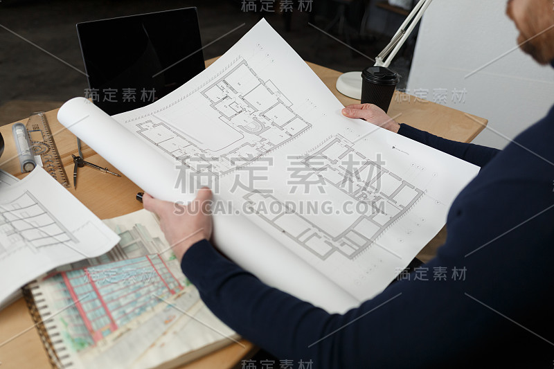 建筑师在办公室里设计蓝图。工程师检查建筑平面图，为建筑工程画草图。长着胡须的英俊男子坐在工作场所的肖