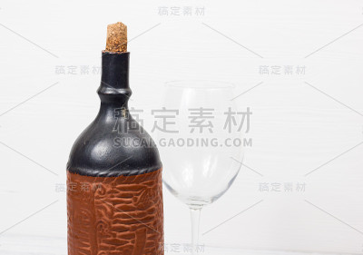 木制背景上的黑酒瓶和玻璃酒杯