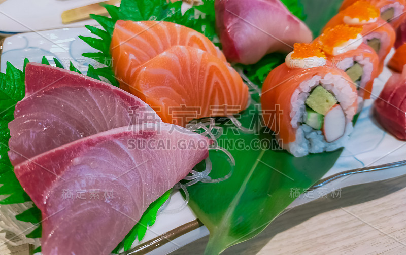 白色盘子上的日本食物。餐厅桌上的三文鱼寿司和生鱼片。新鲜生鱼片、日本醋饭卷配海鲜和蔬菜。健康的日本食