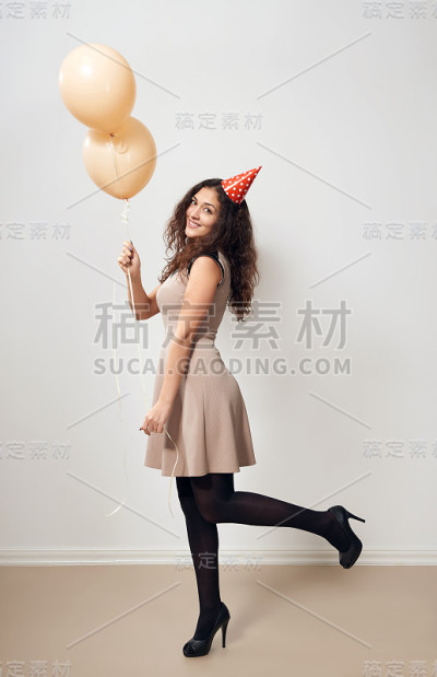 快乐的年轻女人或十几岁的女孩穿着棕色的衣服和氦气气球