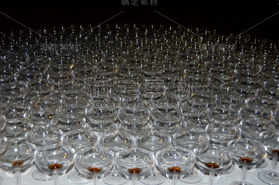 在模糊的灯光背景下，漂亮的平底香槟酒杯放在桌子上。软的焦点。浅景深