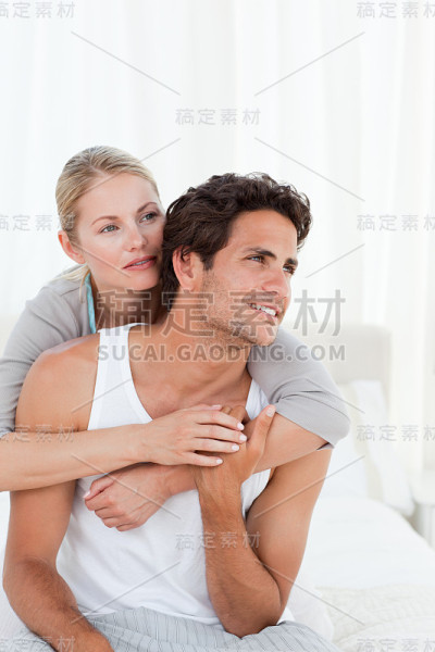 可爱的夫妇在他们的床上拥抱