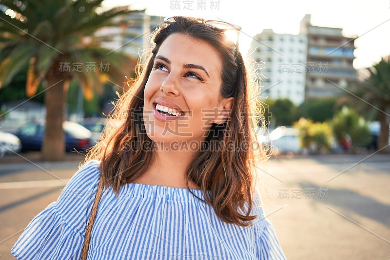 在一个阳光明媚的夏天，年轻美丽的女人快乐地走在城市的街道上