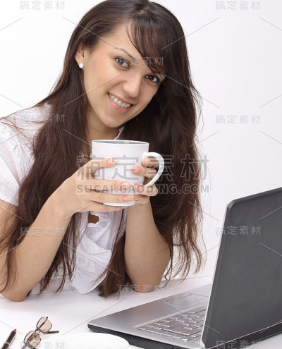 年轻女子拿着一杯茶坐在工作场所