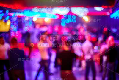 人们跳舞，唱歌，娱乐和放松在夜总会模糊的背景。闪烁的灯光美丽模糊的灯光在舞池放松晚上在俱乐部