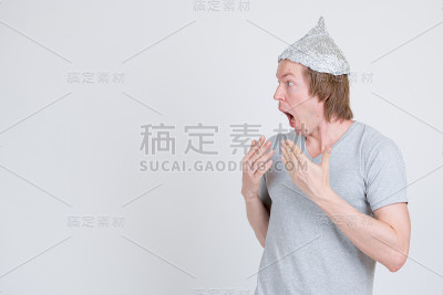 侧面的年轻人与锡纸帽看起来震惊