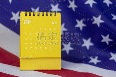 2021年7月翻页日历。以美国国旗为背景进行计划、分配、组织和管理每个日期的桌面日历。