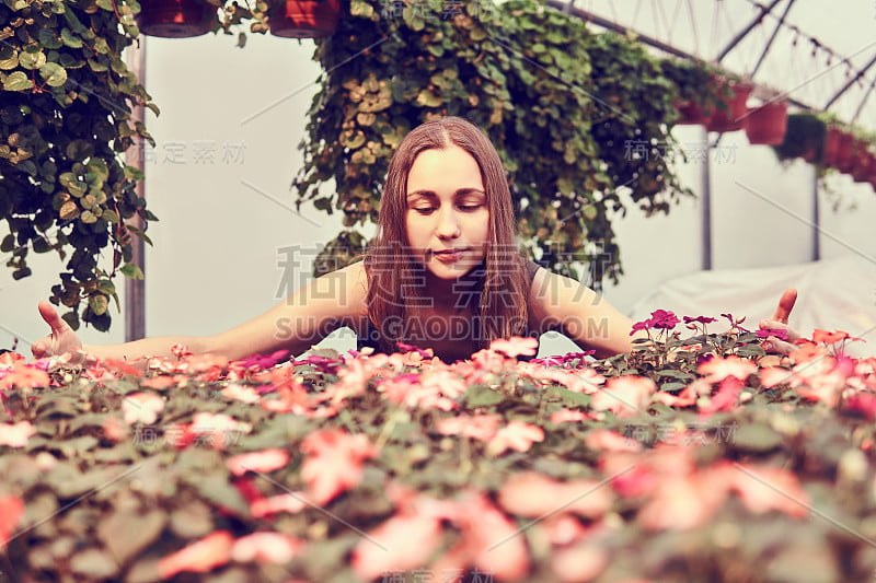 穿着衣服的女人在温室的观赏植物中间