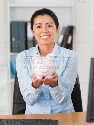 漂亮的女人拿着存钱罐看着镜头