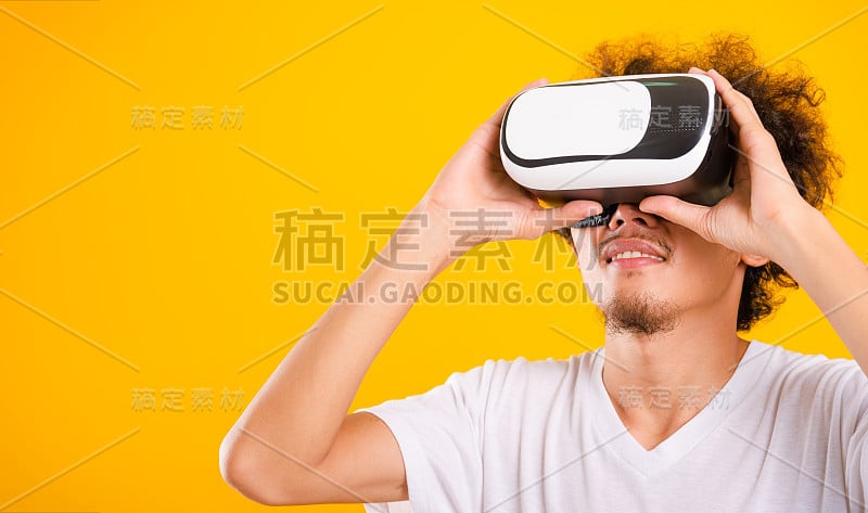 亚洲英俊的卷发，他使用虚拟现实头盔或VR眼镜